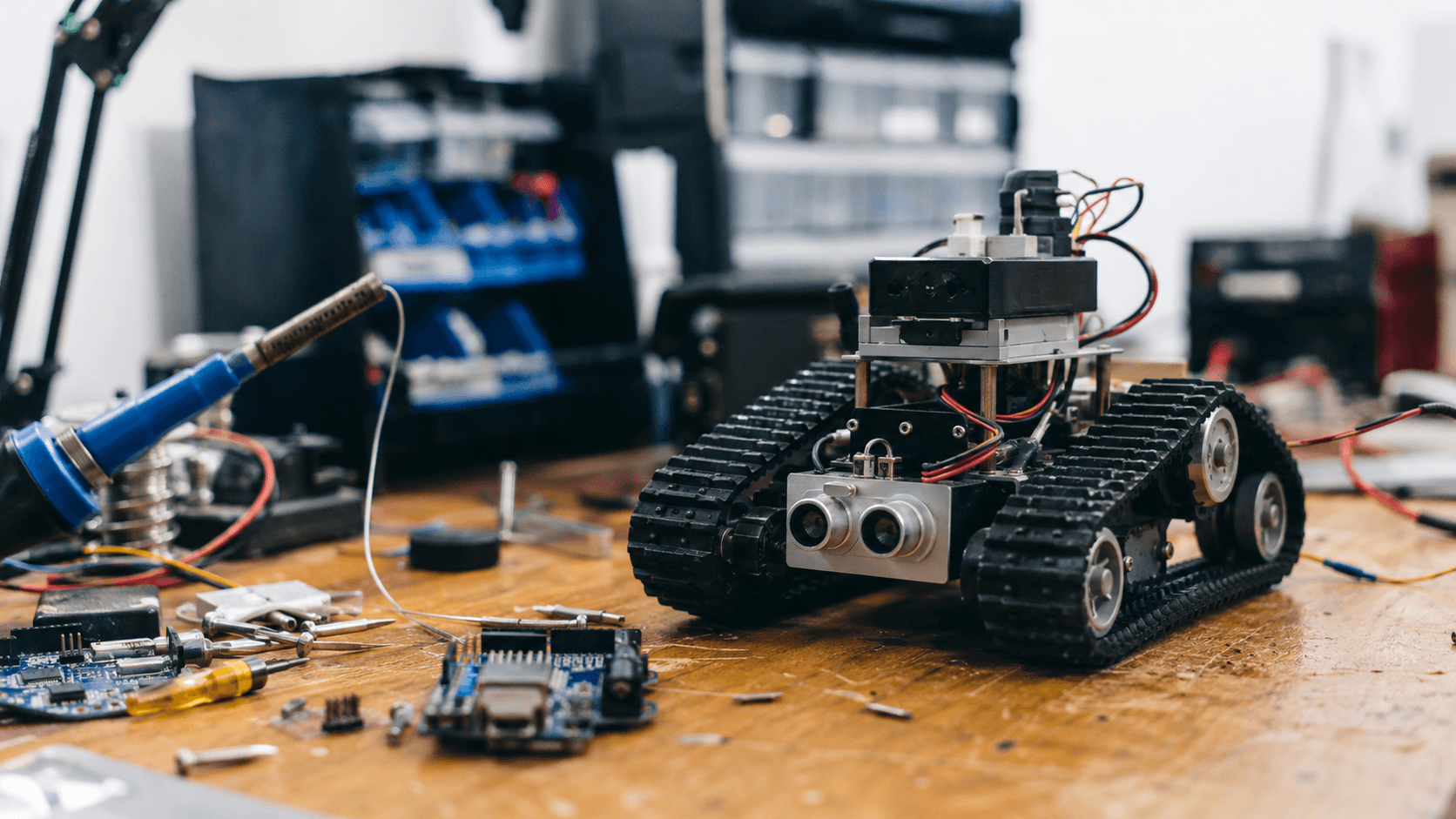 Robot educativo sobre una mesa de trabajo con herramientas y placas electronicas